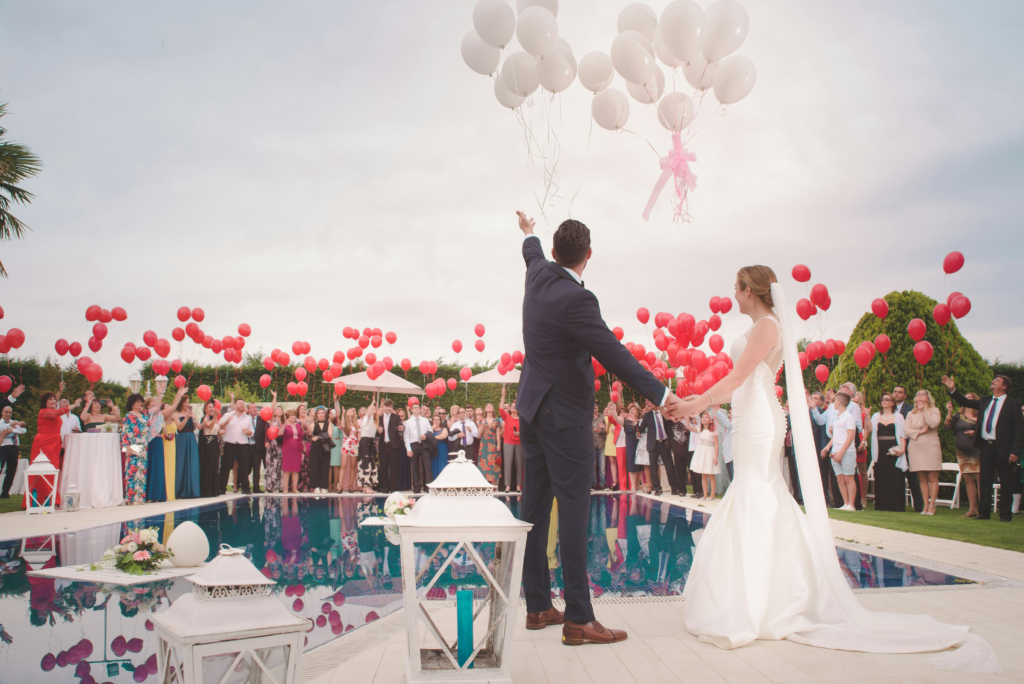 couple letting go on red and white balloons during wedding