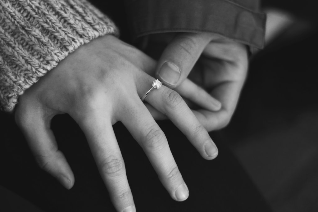 black and white image of a newly engaged couple zoomed in on the ring